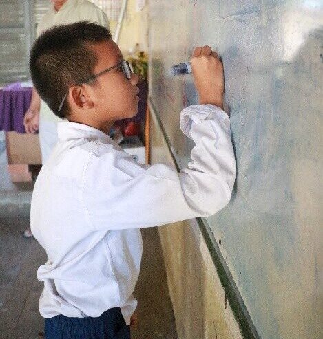 Mr. Leng Bunchhay is writing on a white board in a classroom.