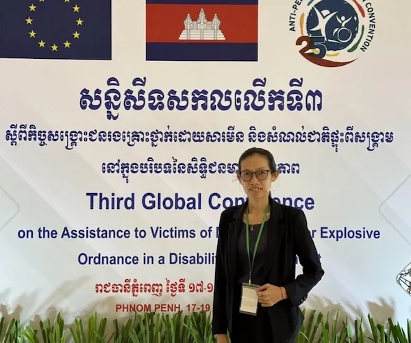 Ms Sreytouch standing in front of a big banner.