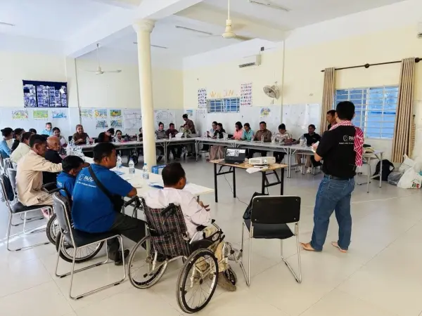 a group of people sitting in a U-shaped table listening to a PAfID staff talking.