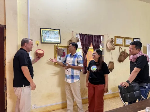 Group of people laughing, looking at an object on the wall.
