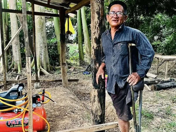 Man with disability standing next to his shop.