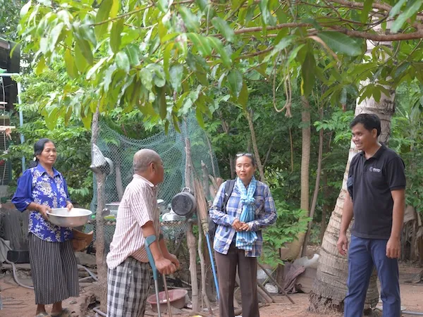 Group of people standing and chatting while smiling.