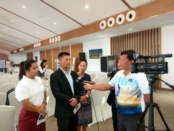 Multiple PAfID members in front of a camera, a journalist is asking a question with a microphone.