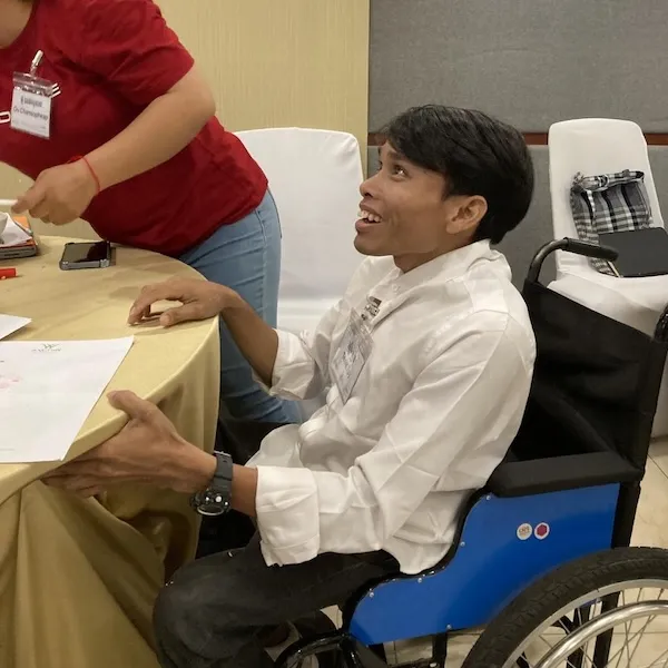 A man sitting on a wheel chair and smiling.