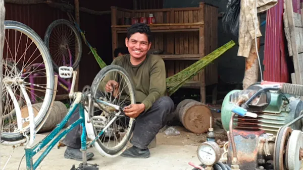 Man with disability smiling. He is repairing a bicycle in his shop.