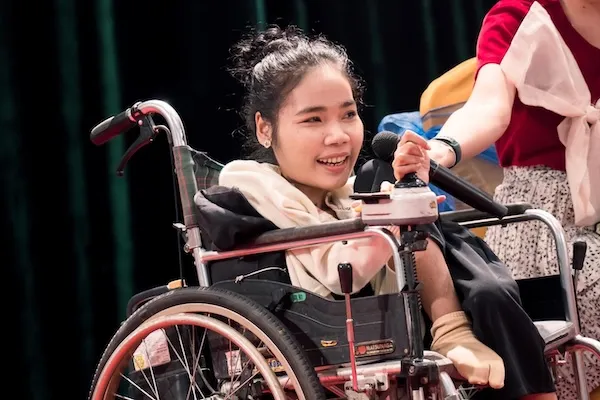 Woman with disability speaking to a microphone.