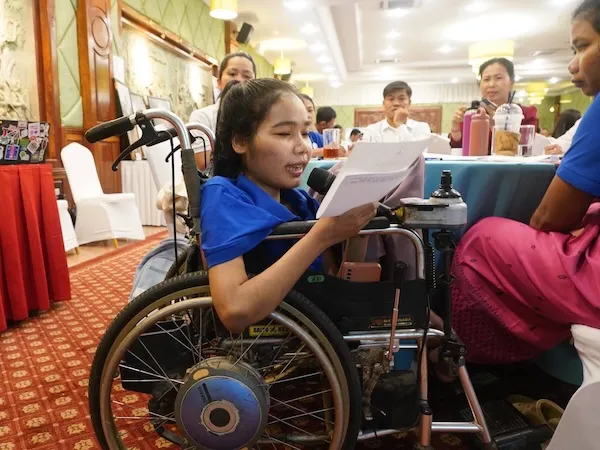 Woman with disability speaking with a microphone.