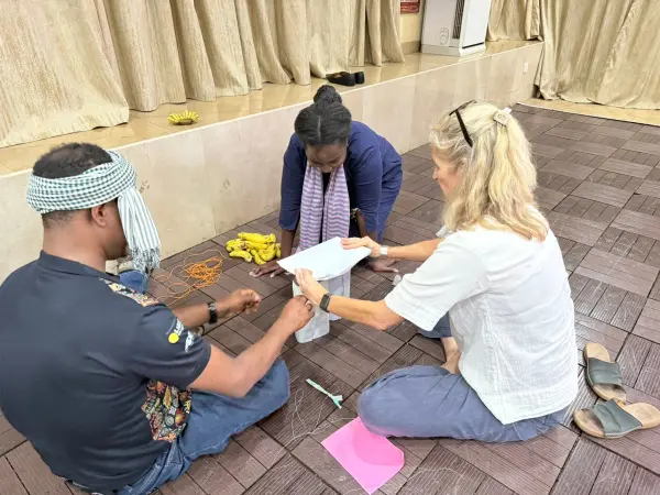 Three people sitting in a circle working with papers.