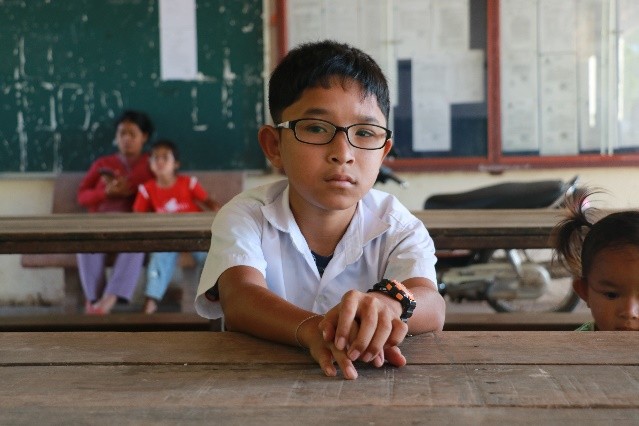 Mr. Chhi Piseth looking at us, he's seated in a class room.