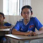 Ms. Minh Sothana is seated in her classroom and is looking at us.