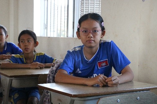 Ms. Minh Sothana is seated in her classroom and is looking at us.