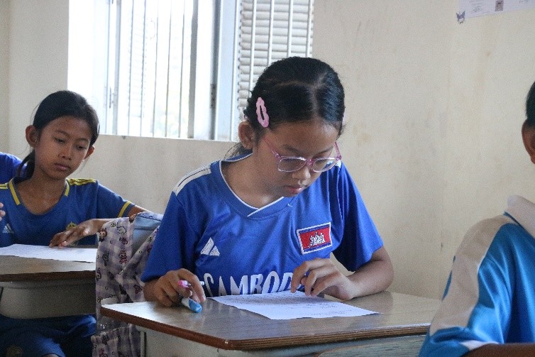 Ms. Minh Sothana is focused on her notebook in her classroom.