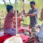 Mr Sim Thoun and his wife working on their sugar cane juice machine. She is handing a bag to a customer.