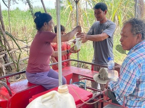 Mr Sim Thoun and his wife working on their sugar cane juice machine. She is handing a bag to a customer.