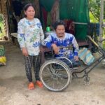 Mr Soeun Da is sitting in an adapted wheelchair, his mother is standing next to him.
