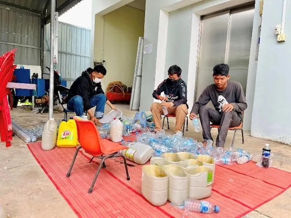 Three men selecting plastic from a pile of plastic bottle.