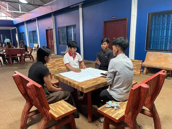 four people sitting around a bench and having a discussion