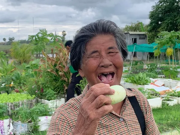 A woman is about to eat a fruit, she is smiling.