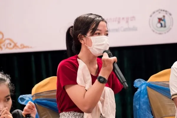 Woman with disability holding a microphone and speaking.